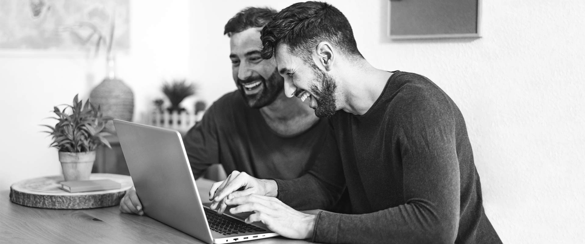Two men smiling while chatting on the computer